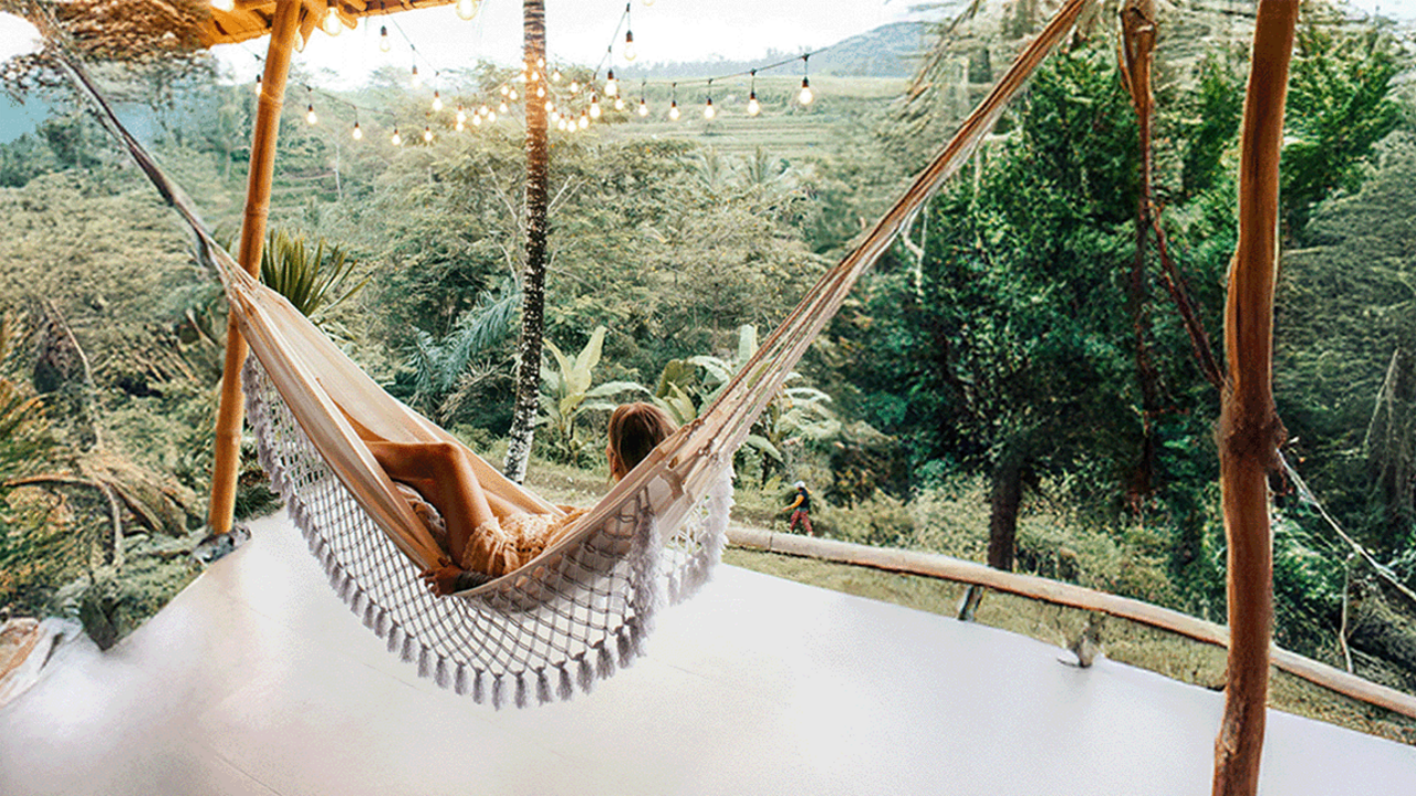Žena se opušta u visećoj mreži s pogledom na zelenu prirodu
