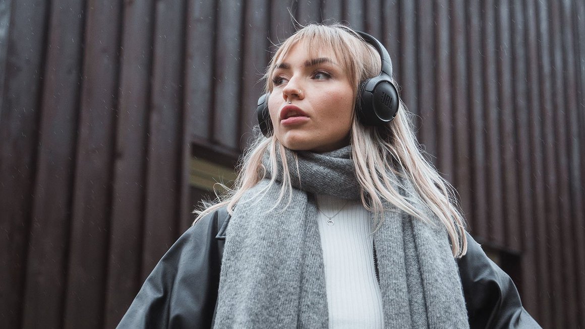 Mlada žena sa slušalicama gleda u daljinu