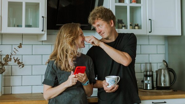 Žena i muškarac stoje u kuhinji i smiju se - zajednički račun