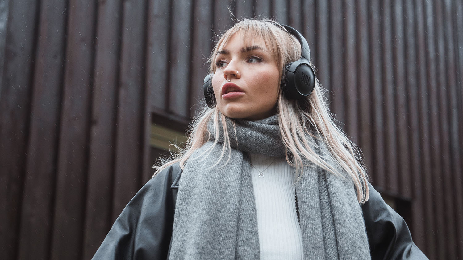 Stvaranje bogatstva s malo novca: Prvo i najvažnije Mlada žena sa slušalicama gleda u daljinu