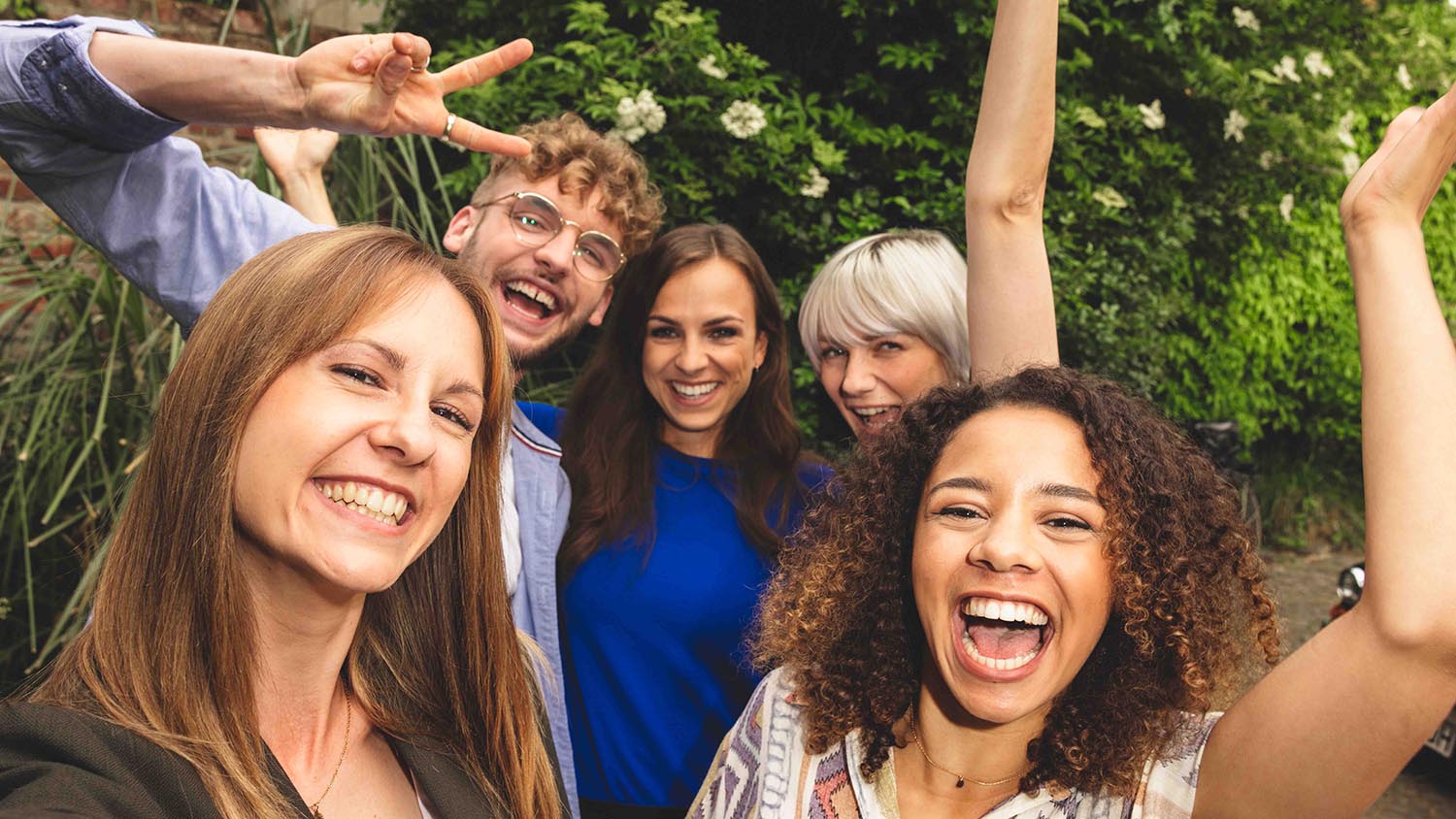 Planiranje odmora s prijateljima - kako to funkcionira Pet prijatelja stoje blizu jedan uz drugog i smiju se u kameru