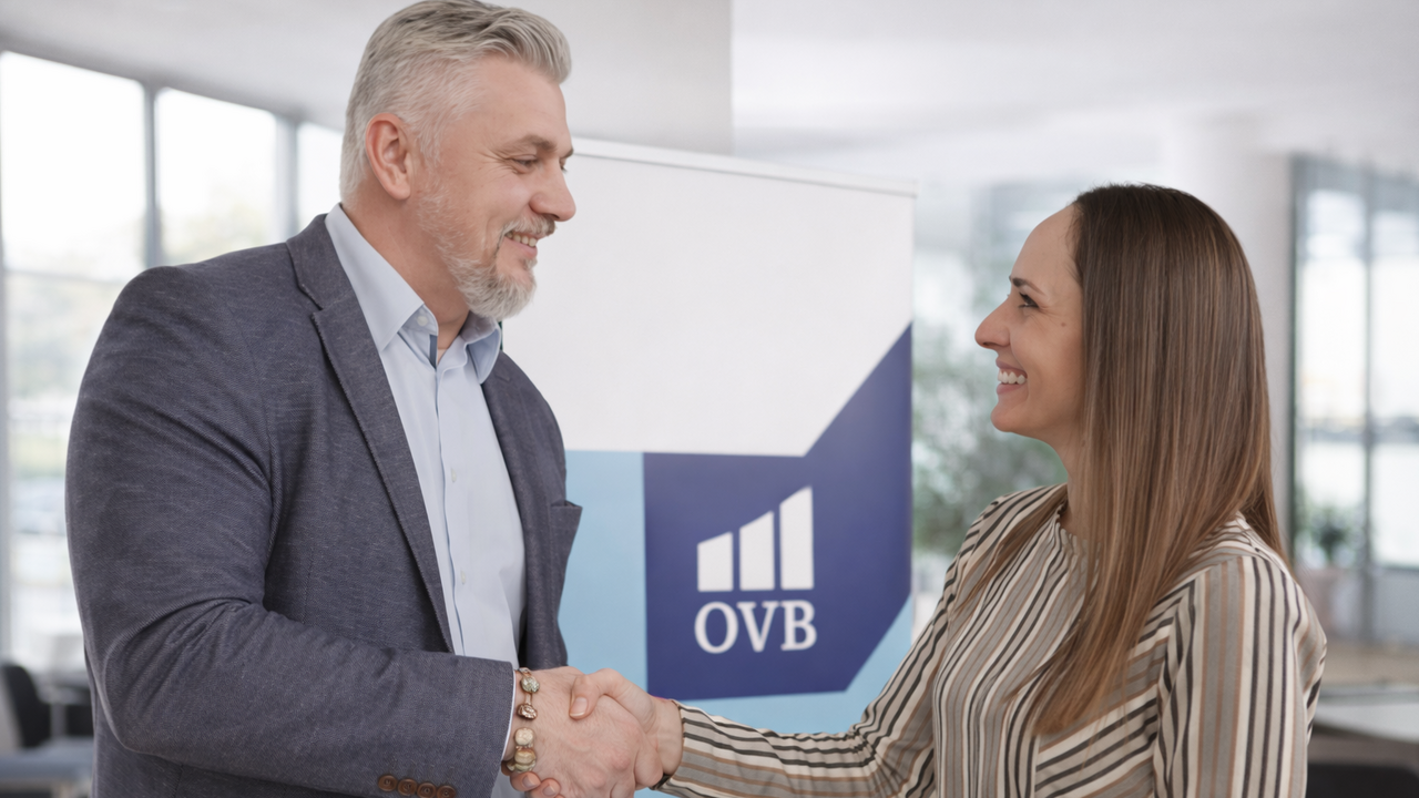 Muškarac i žena se rukuju ispred OVB roll-up bannera u poslovnom okruženju
